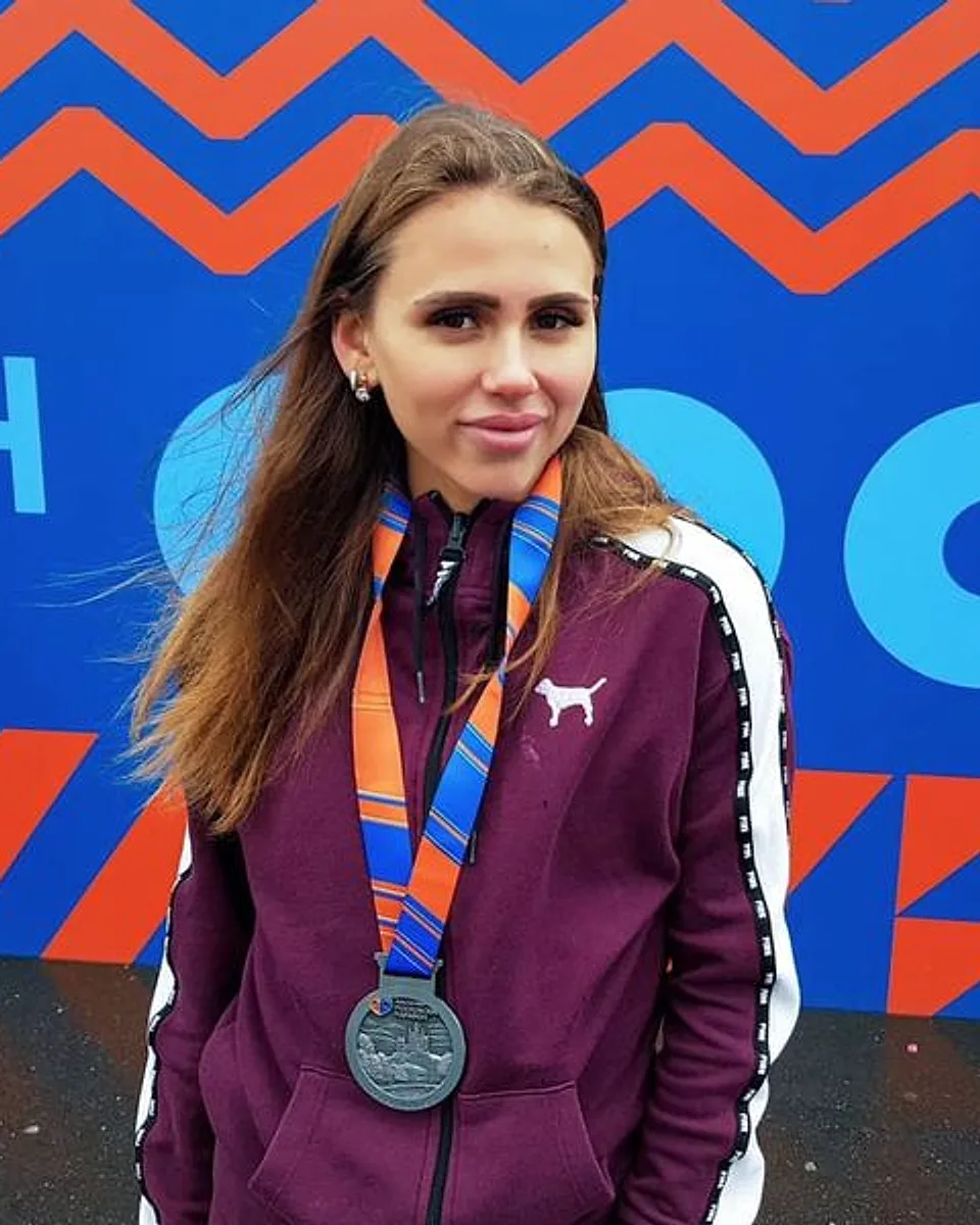 Анастасия Головина с медалью финишёра на фоне баннера марафона